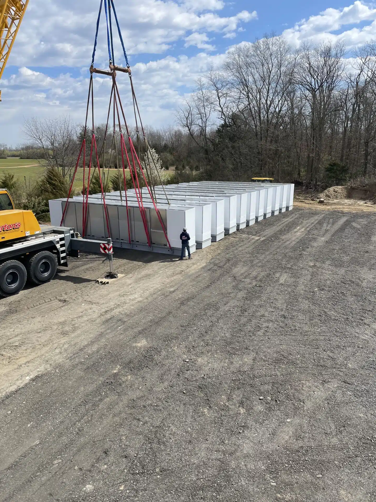 Crane staging large industrial units in a fenced outdoor storage yard